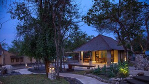 A cozy outdoor seating area with stone pillars, a thatched-roof structure, and a well-maintained garden. - Nusabay Menjangan by WHM (Sumberklampok)