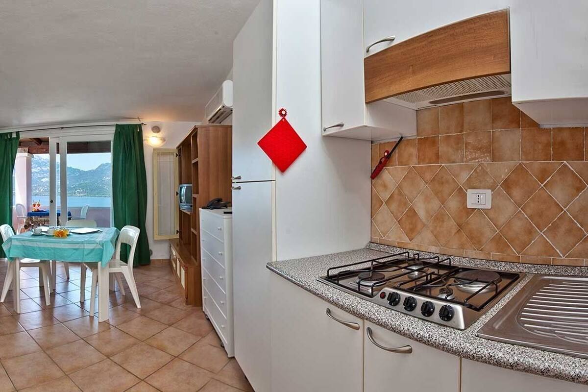 A compact kitchen with a gas stove, white cabinets, and a dining area with a table and chairs.