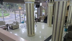 Un vestíbulo con mostrador de recepción, zona de estar y escalera.