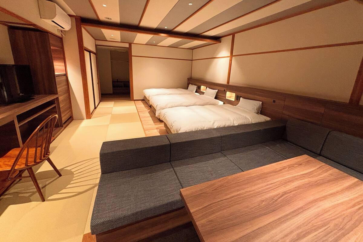 Une chambre avec deux lits, un canapé, une télévision et une table en bois.