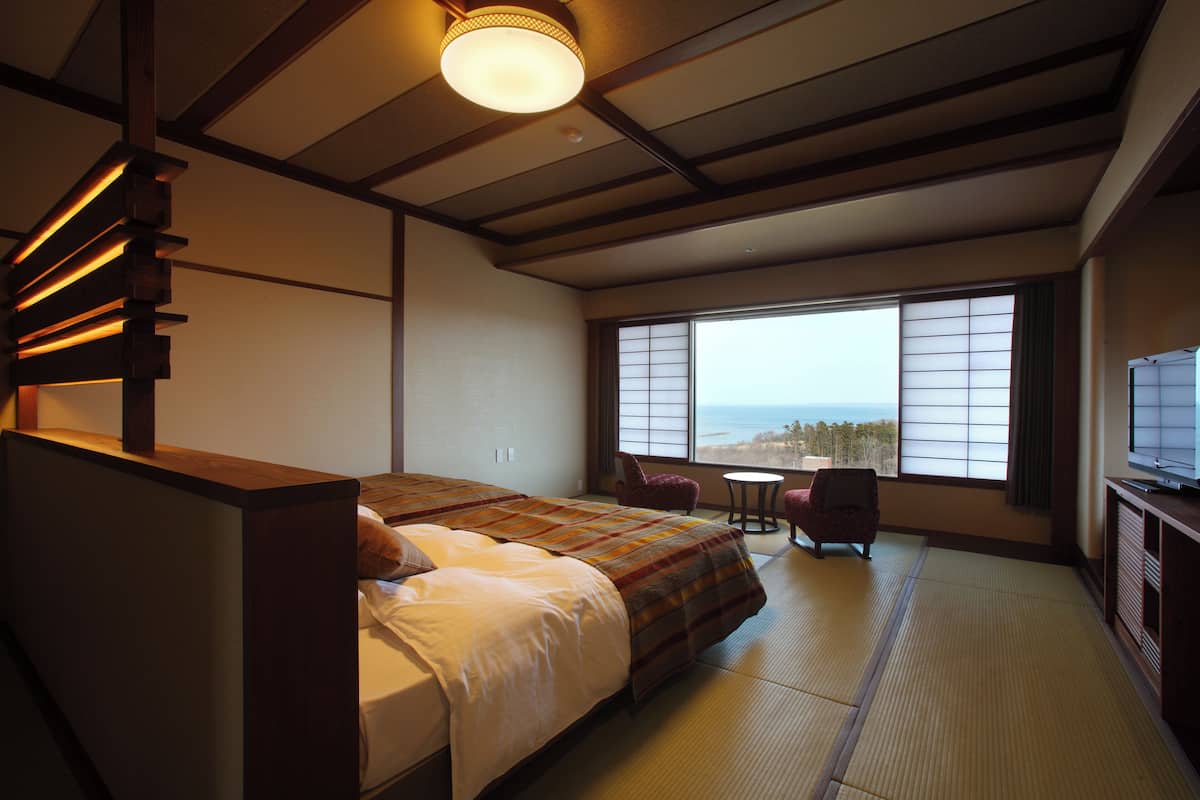 Une chambre d’hôtel avec un lit, une chaise, une petite table et un téléviseur.