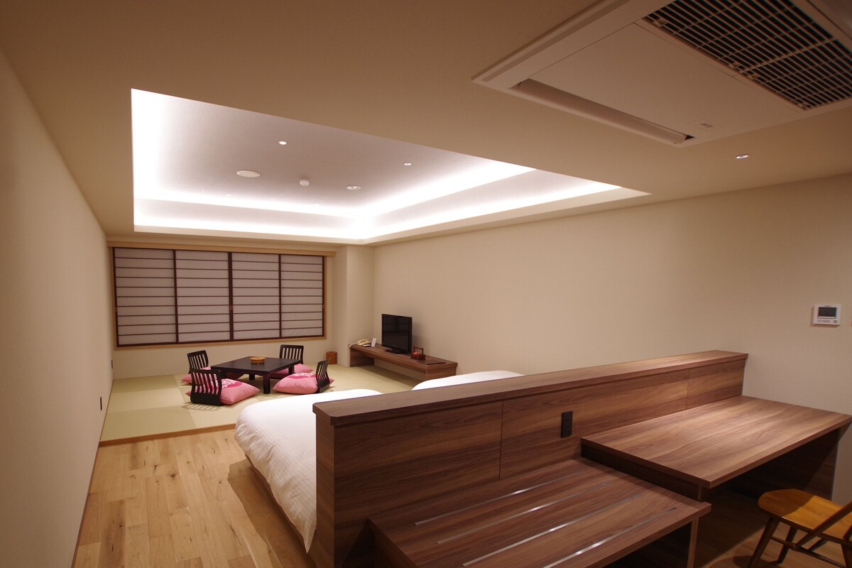 Ein modernes Schlafzimmer mit Bett, Schreibtisch und Fernseher.