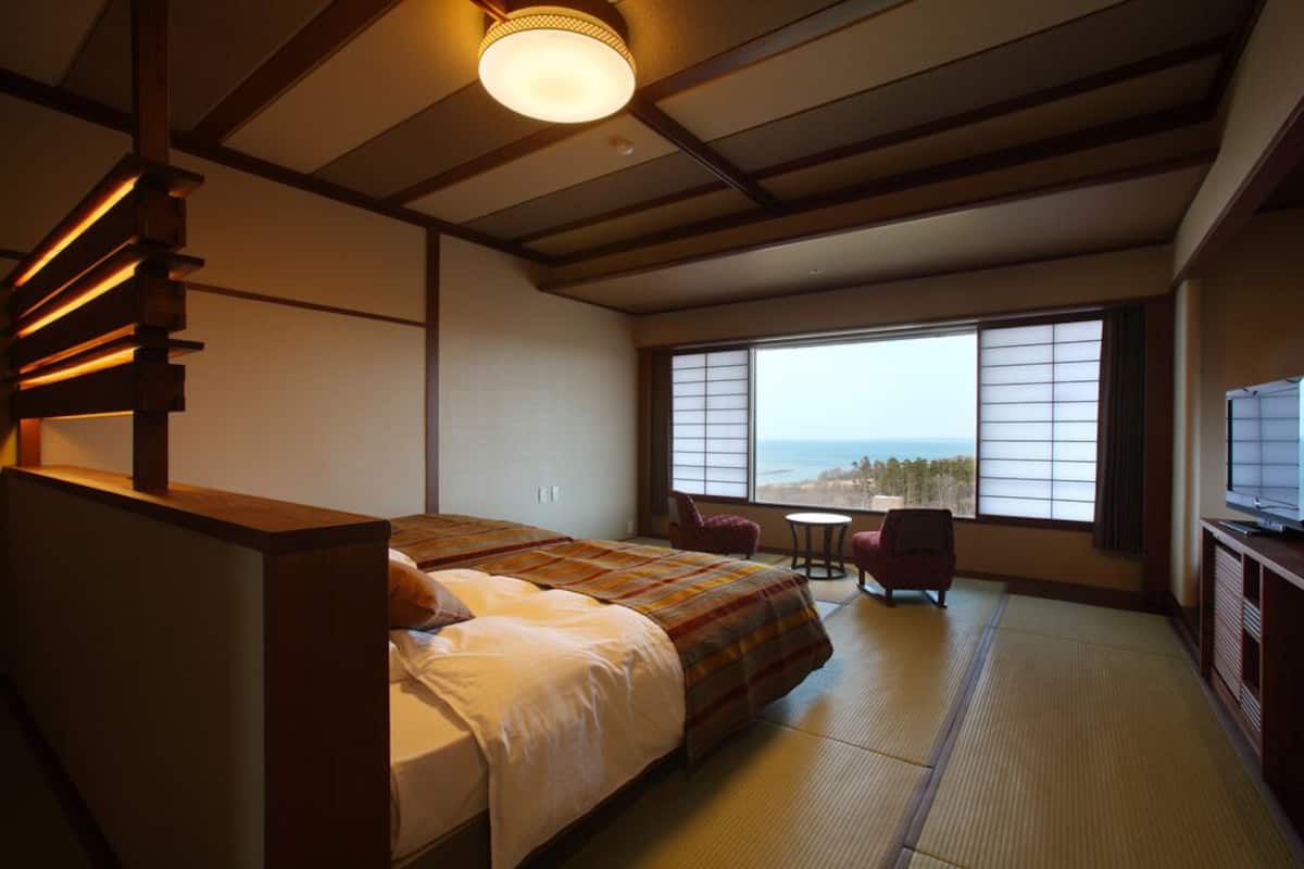 Une chambre d’hôtel avec un lit, une télévision, une fenêtre donnant sur un paysage agréable et une petite table.