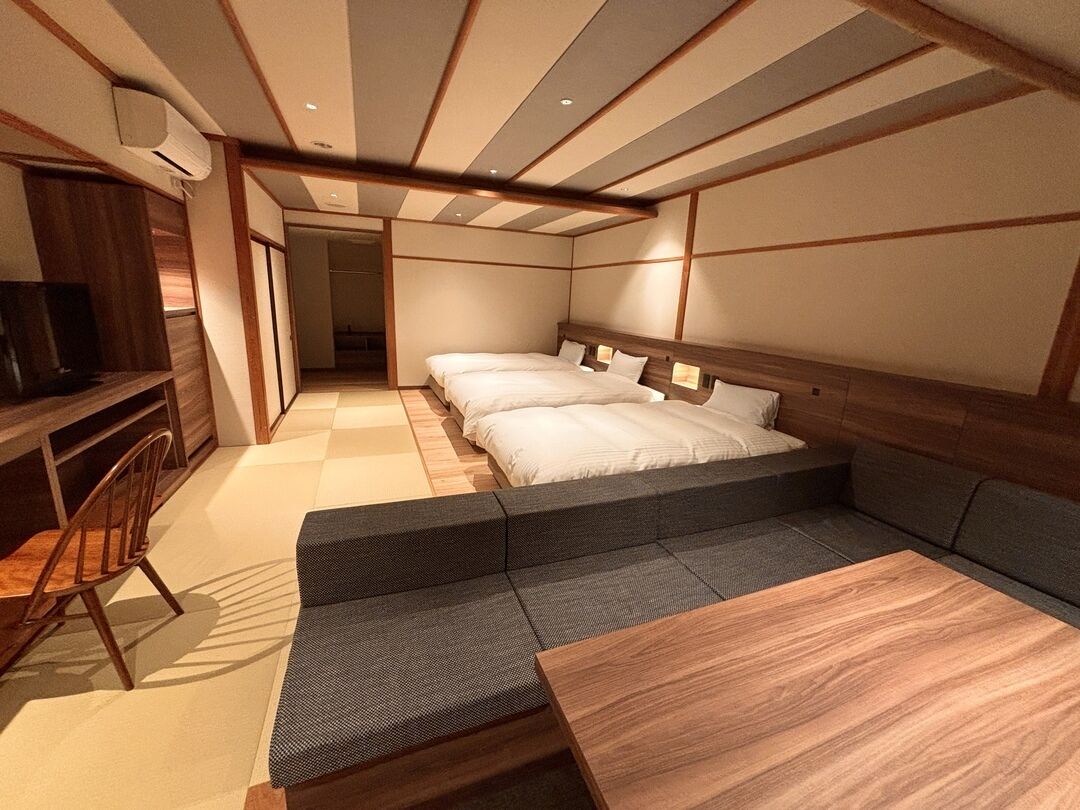 A room with a bed, a desk, a chair, and a sofa.