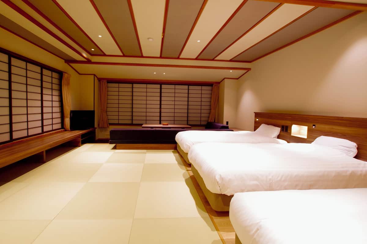 Une pièce de style japonais traditionnel, avec un sol recouvert de tatamis, un futon servant de lit, une tête de lit en bois et des paravents en papier de riz (shoji).