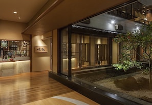 A modern interior with a reception desk, a glass partition, and a small water feature.