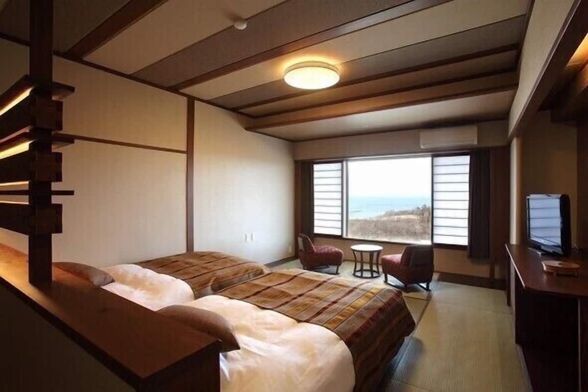 Une chambre avec deux lits, un bureau, une chaise et une vue sur la mer.