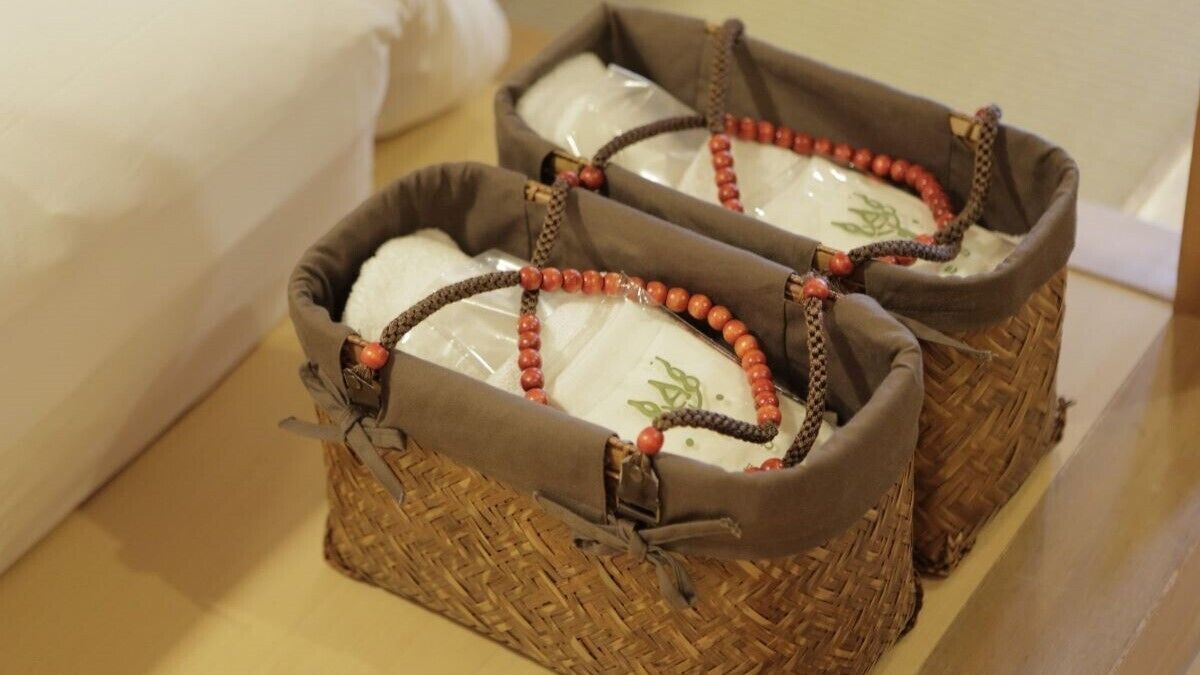 Two woven baskets with handles, each containing a white object with green designs.