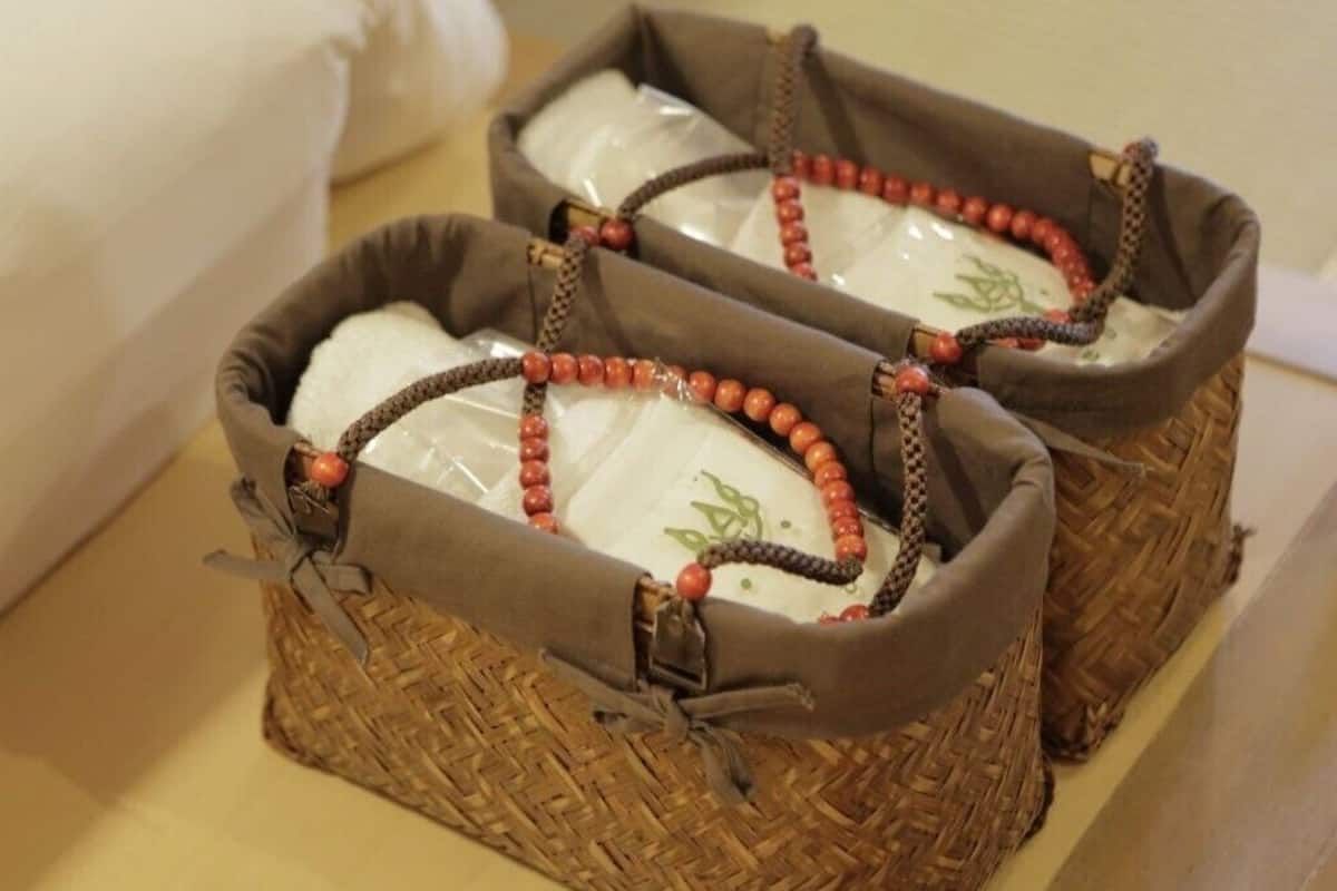 Deux paniers tressés dotés de poignées, chacun contenant un objet blanc orné de motifs verts.