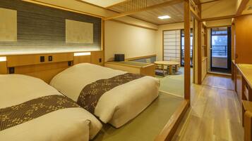 Een traditionele Japanse kamer met tatami vloeren, een lage tafel met kussen en een schuifdeur naar een balkon.