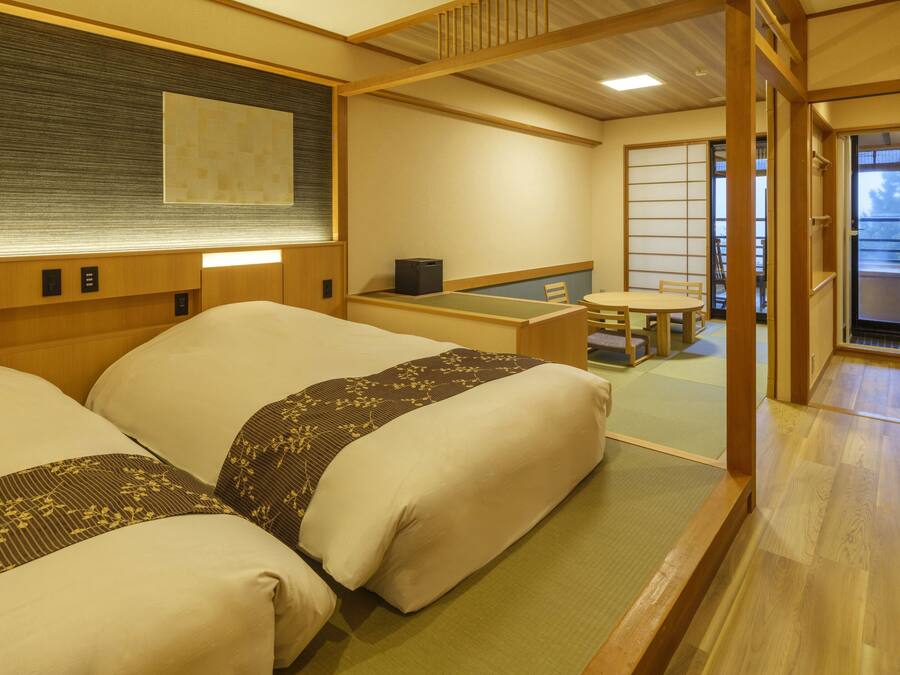 Een traditionele Japanse kamer met tatami vloeren, een lage tafel met kussen en een schuifdeur naar een balkon.