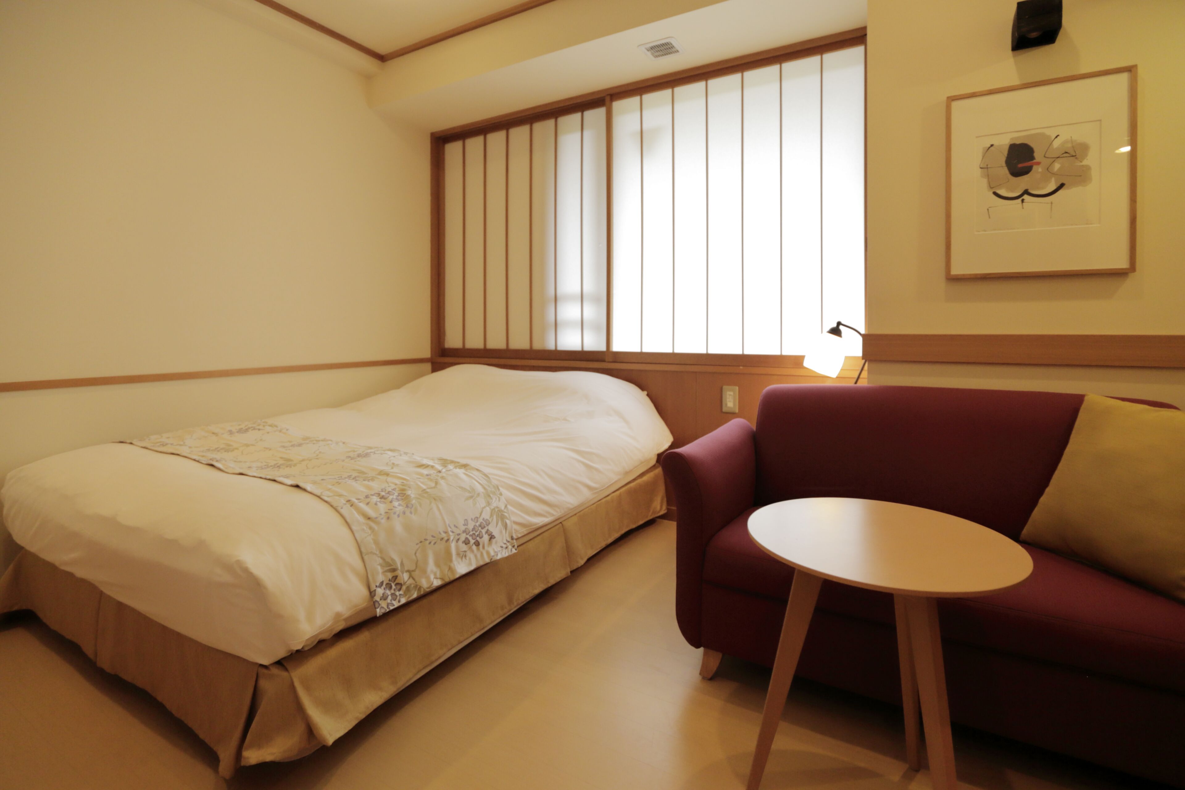 Un dormitorio con una cama, un sofá rojo y una pequeña mesa redonda.