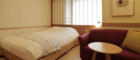 A bedroom with a bed, a red sofa, and a small round table.