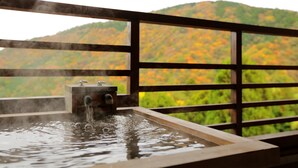 A hot spring with a wooden railing and a view of a forested hillside. - Mizunoto (Hakone)