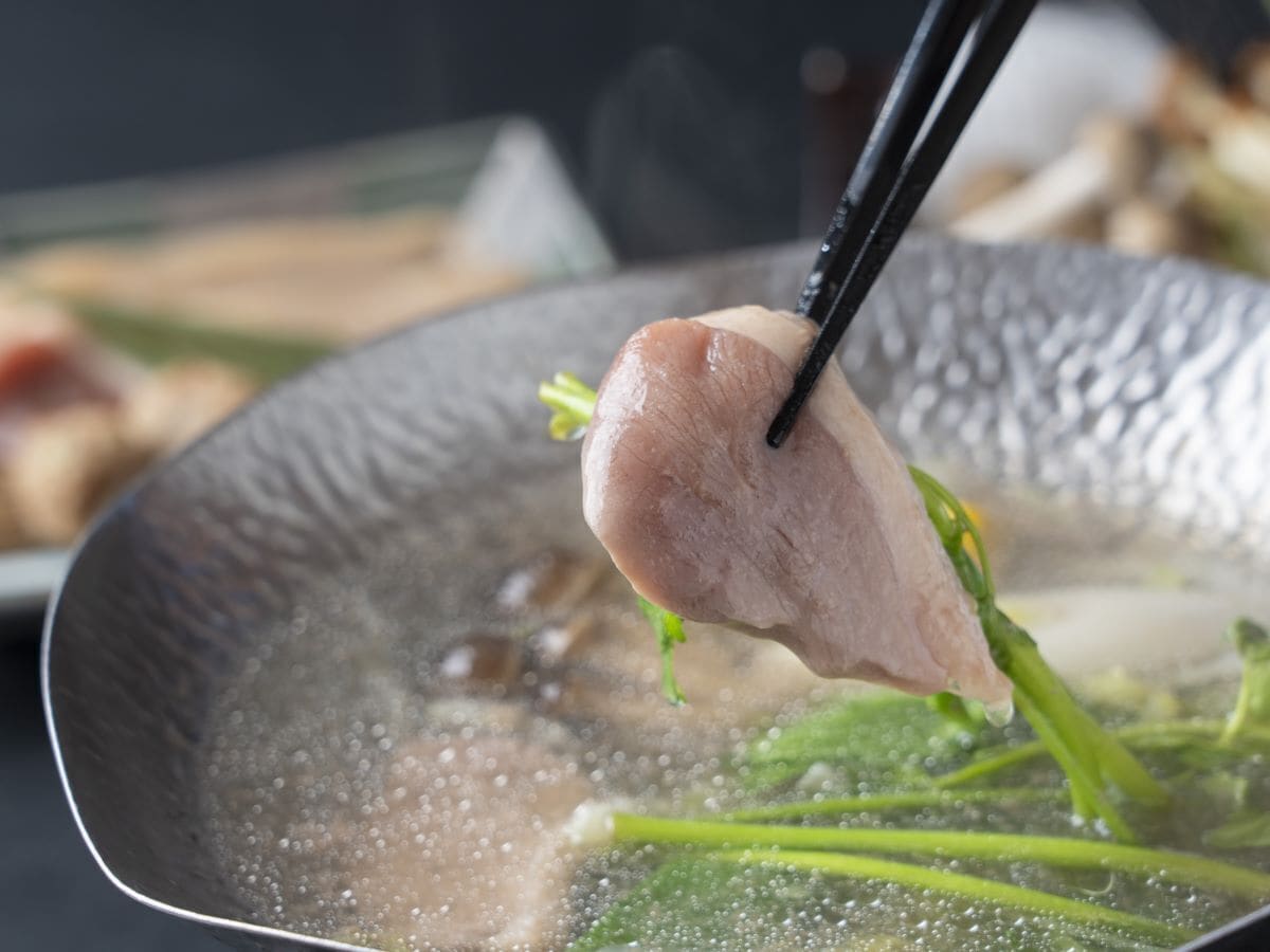 A close-up of a cooking pan with a piece of meat and green vegetables.