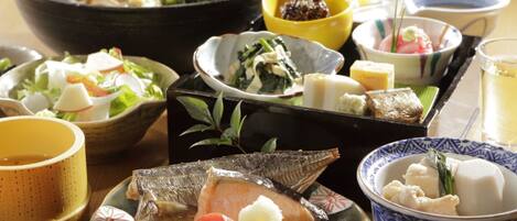 A variety of dishes including fish, vegetables, and rice, served on traditional Japanese plates and bowls.
