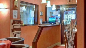 A reception area with a desk, computer, and chairs. - Hôtel de l'île (Custines)