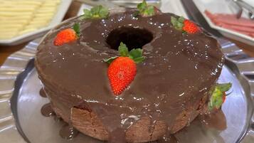 A chocolate bundt cake with strawberries on a metal plate.