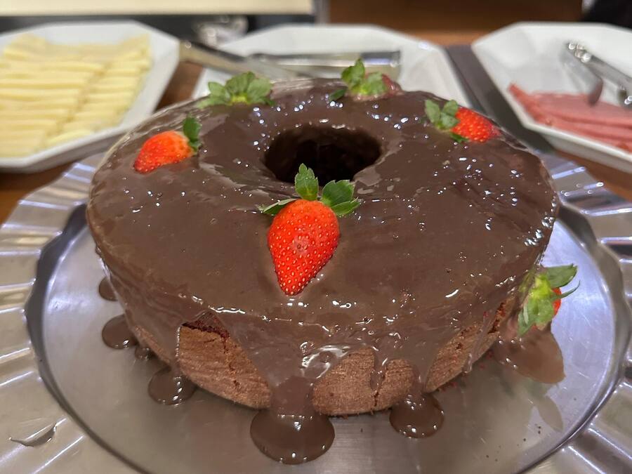 A chocolate bundt cake with strawberries on a metal plate.
