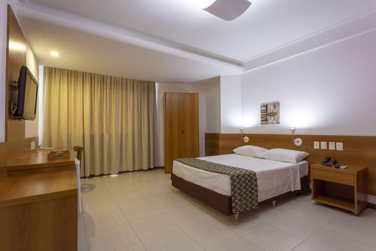 Una habitación de hotel con cama, mesita de noche y escritorio con silla.