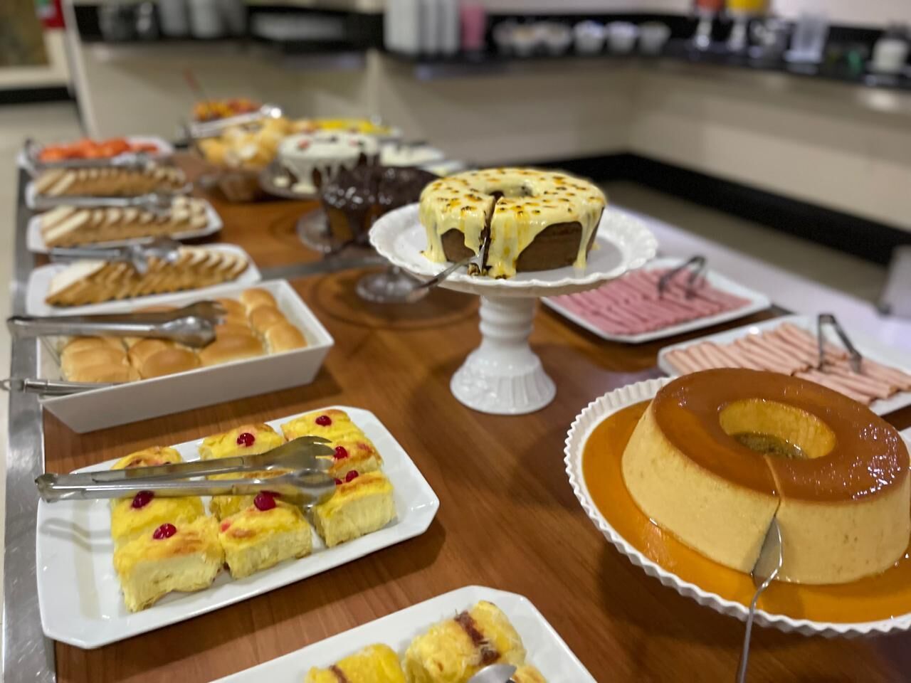 Una mesa de buffet con diversos postres, incluyendo un flan, un pastel de caramelo y un pastel de queso.