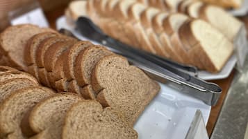 A buffet with various sliced breads and pastries.