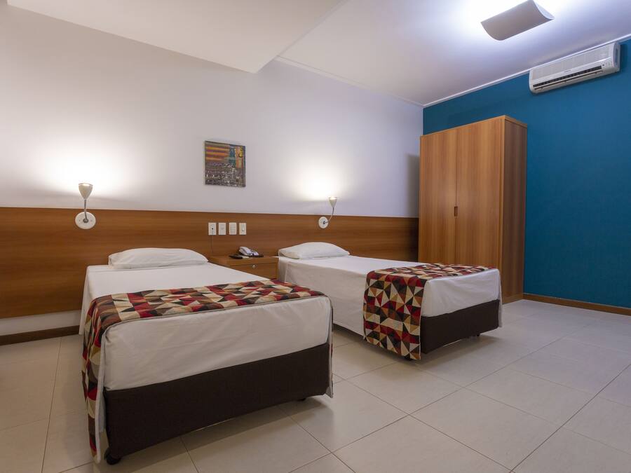 Una habitación de hotel con dos camas, un armario de madera y un cuadro de un paisaje urbano en la pared.