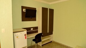 Une petite pièce comprenant un bureau, une chaise, un téléviseur fixé au mur et une armoire.