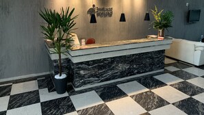 Un comptoir d’accueil avec un plateau en marbre, deux plantes en pot et un luminaire moderne.