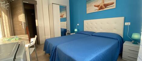 A bedroom with two beds, a desk, a chair, and a painting of a starfish on the wall.