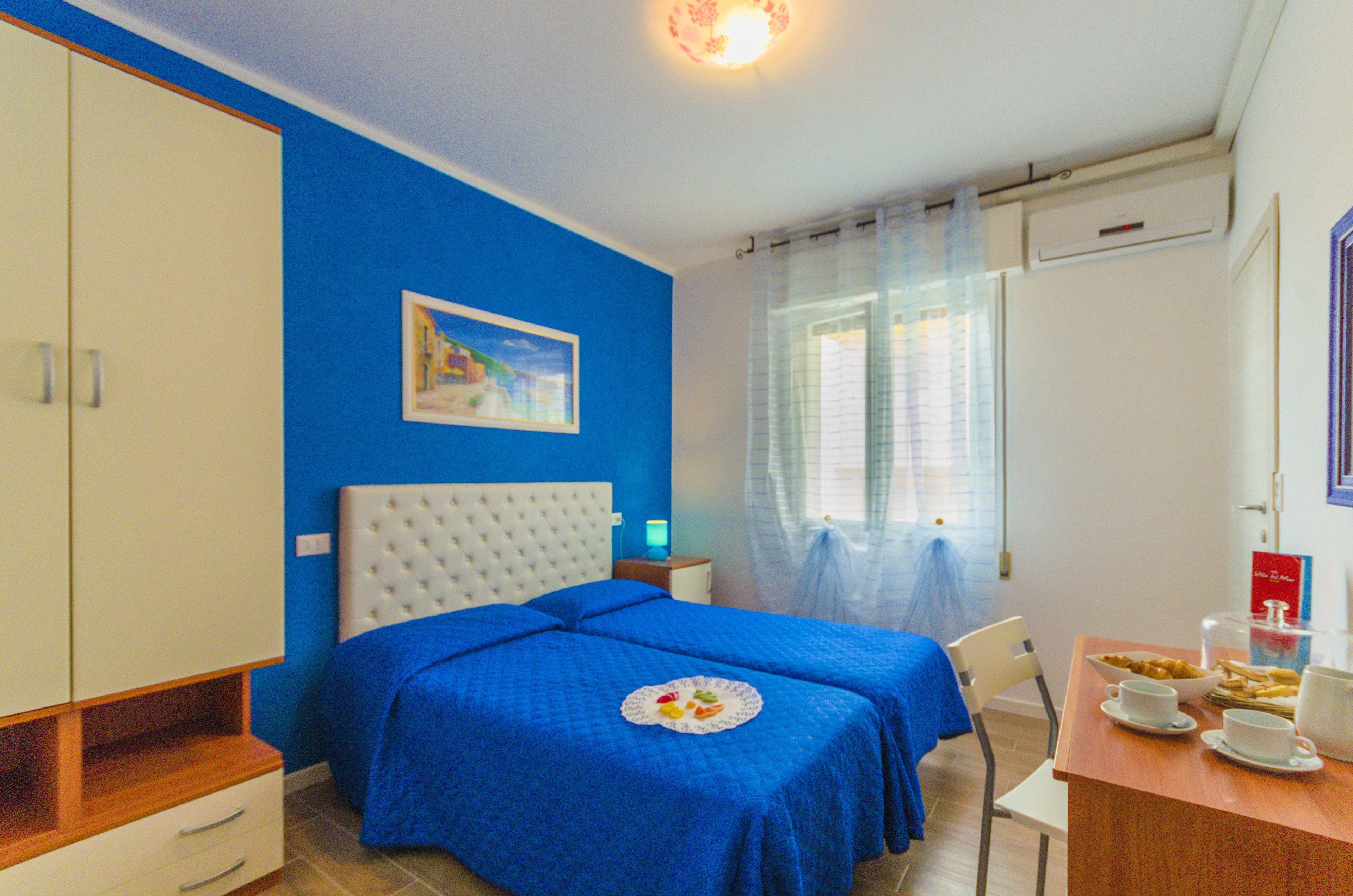 Una camera da letto con un letto, un comodino, una sedia, un tavolo imbandito per la colazione e un quadro appeso alla parete.
