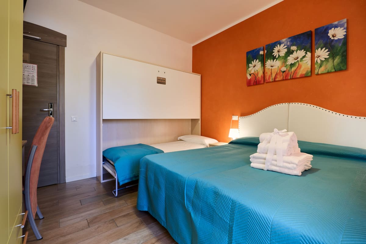 Habitación de hotel con dos camas, un armario, un cuadro en la pared y un montón de toallas.