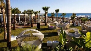 Un resort con aree salotto all'aperto, palme e vista sul mare.