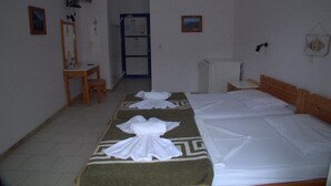 A hotel room with two beds, a desk, a chair, a TV, and a refrigerator. - Hotel Sofia (Samos)