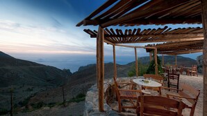 A wooden pergola with a table and chairs overlooking a mountainous landscape. - Thalori (Gortyna)