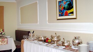 A dining area with a long table set for a meal, featuring silverware, plates, and a centerpiece of fruits and flowers. - Coloso Potosi (Potosi)