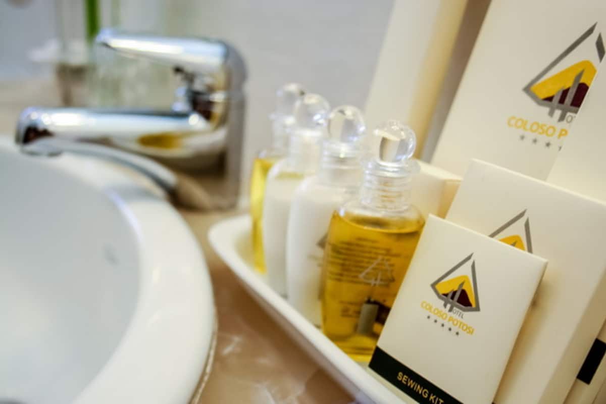 Un baño con un lavabo blanco, un grifo cromado y una bandeja con artículos de aseo, incluyendo una botella de loción y cajas de una marca.