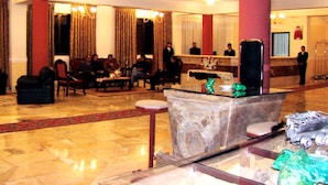 A lobby with a reception desk, seating area, and a large pillar. - Coloso Potosi (Potosi)