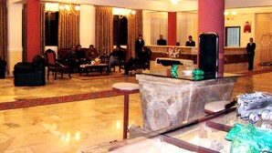 A lobby with a reception desk, seating area, and a large pillar. - Coloso Potosi (Potosi)