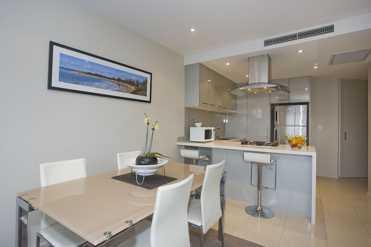 A modern kitchen with a central island, white cabinetry, and a microwave.
