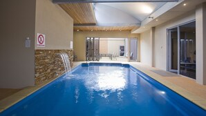 An indoor swimming pool with a brick wall, a no diving sign, and a view of a patio area with outdoor seating. - 7 Bell Street Apartments (Torquay)