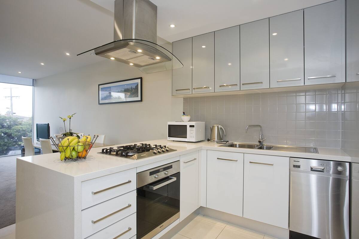 A modern kitchen with white cabinetry, a gas stove, a microwave, and a dishwasher.