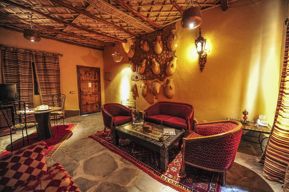 A traditional interior with a thatched ceiling, patterned rugs, and a wall adorned with pottery.