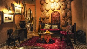 A traditional interior with a stone wall, a wooden door, and a checkered floor. - Kasbah Hotel Xaluca Arfoud (Aarab Sebbah Ziz)