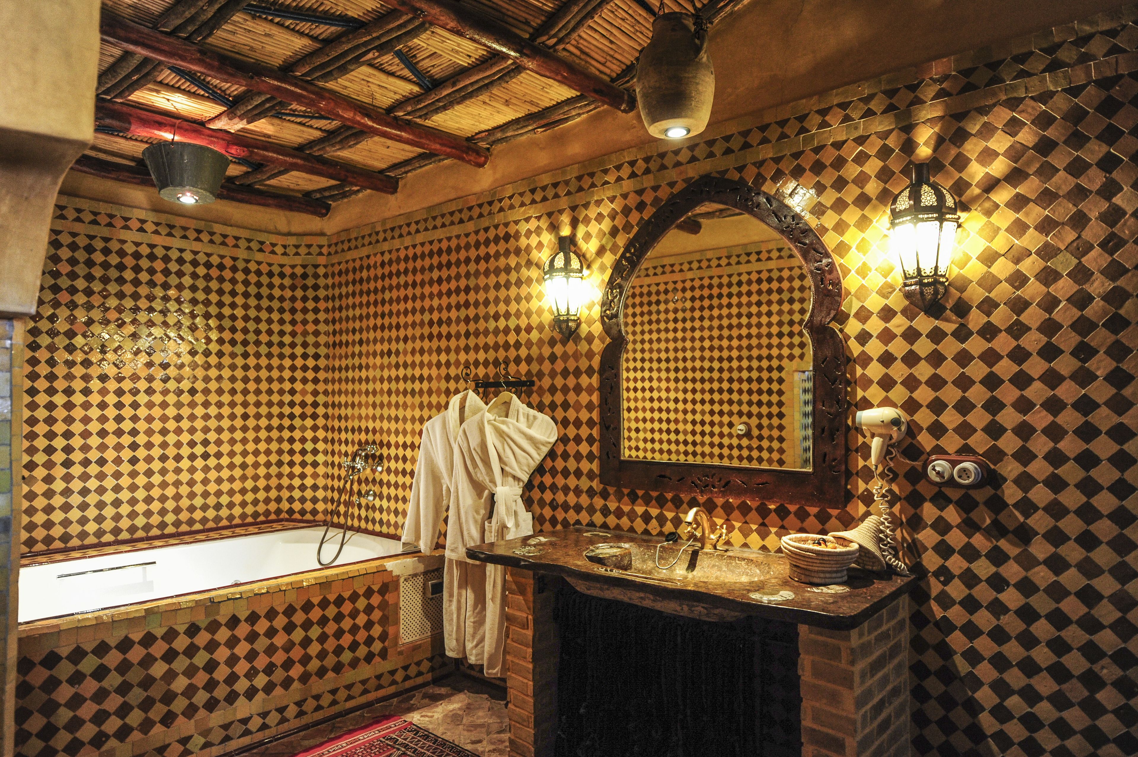 Un baño con piso de baldosas de diseño cuadriculado, un espejo grande, una bañera y un lavamanos de estilo vintage.