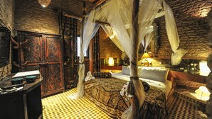 A traditional room with a canopy bed, checkered floor, and ornate wooden doors. - Kasbah Hotel Xaluca Arfoud (Aarab Sebbah Ziz)