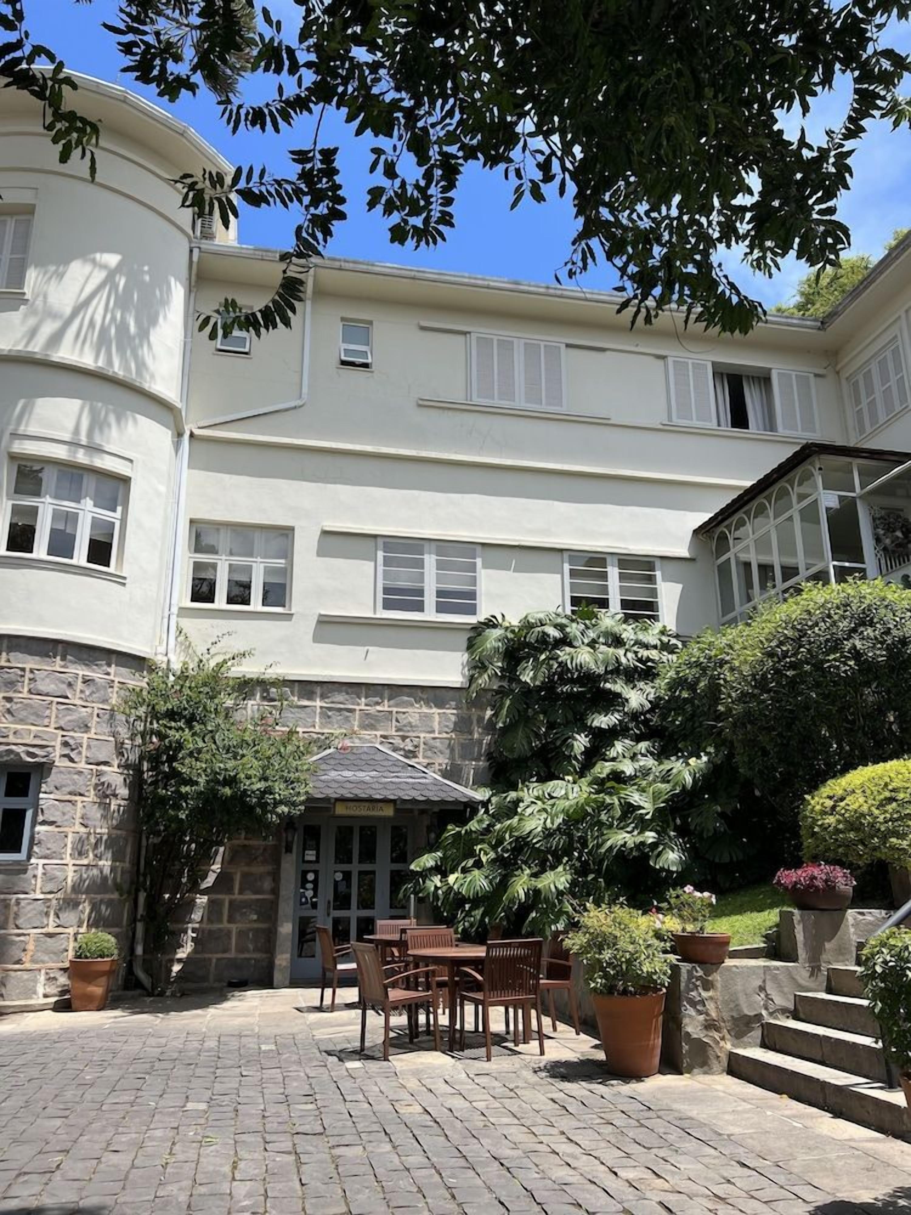 Um edifício com fachada de pedra, um alpendre com mobiliário exterior e uma placa com a inscrição 'HOTEL'.