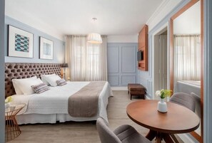 A hotel room with a large bed, a round dining table, a TV mounted on the wall, and a window with curtains. - Hotel Casacurta (Garibaldi)