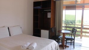 A hotel room with a bed, a wardrobe, a small table with two chairs, and a balcony with a view.