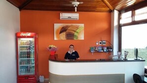 A reception area with a Coca-Cola refrigerator, a painting on the wall, and a window with a view.
